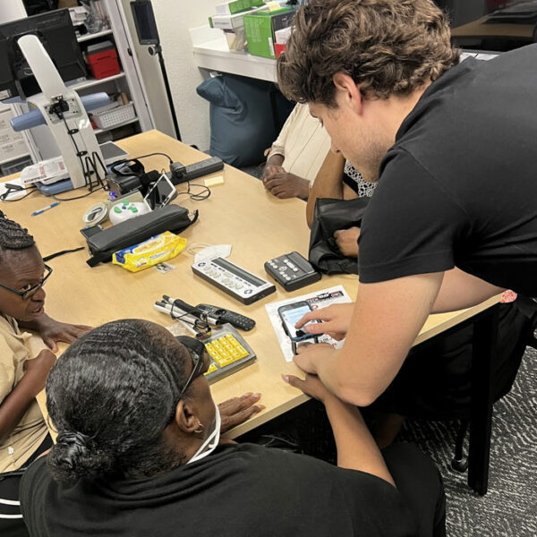 A TechOWL employee shows a woman how to find reading accessibility features on her phone