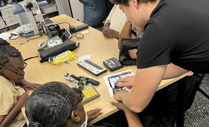 A TechOWL employee shows a woman how to find reading accessibility features on her phone